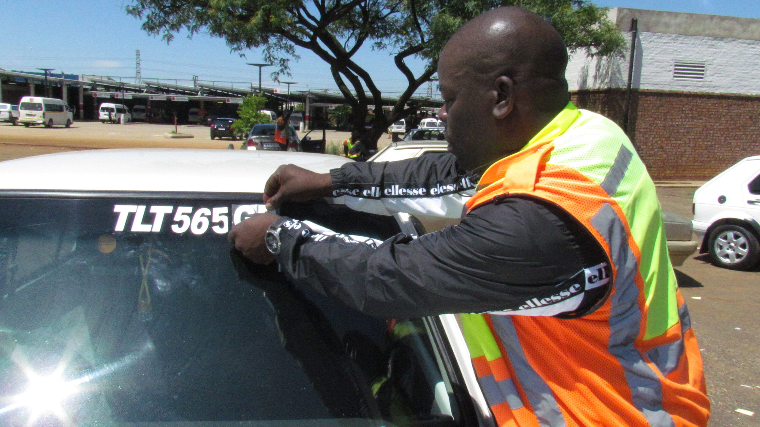 Executive member of 4 plus 1 taxi association putting a visible number plate sticker on the taxi in Mamelodi West