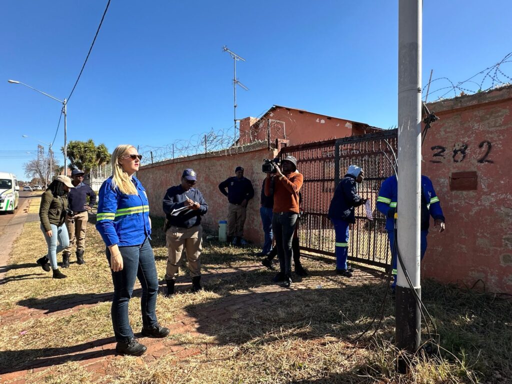 MMC Jacqui Uys with Tshwane Metro Police and officials outside a house whose electricity supply was due to be disconnected in Laudium