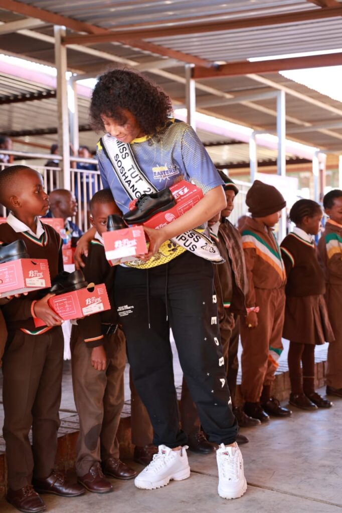 Miss Tshwane University of Technology Soshanguve campus Sharon Maluleke handing out school shoes to Shalom Primary School learners