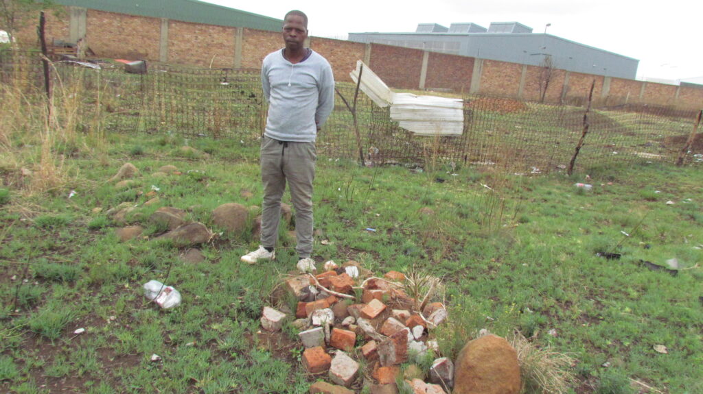 Resident of Plot 61 Smith informal settlement standing next to the graveyard of a relative 