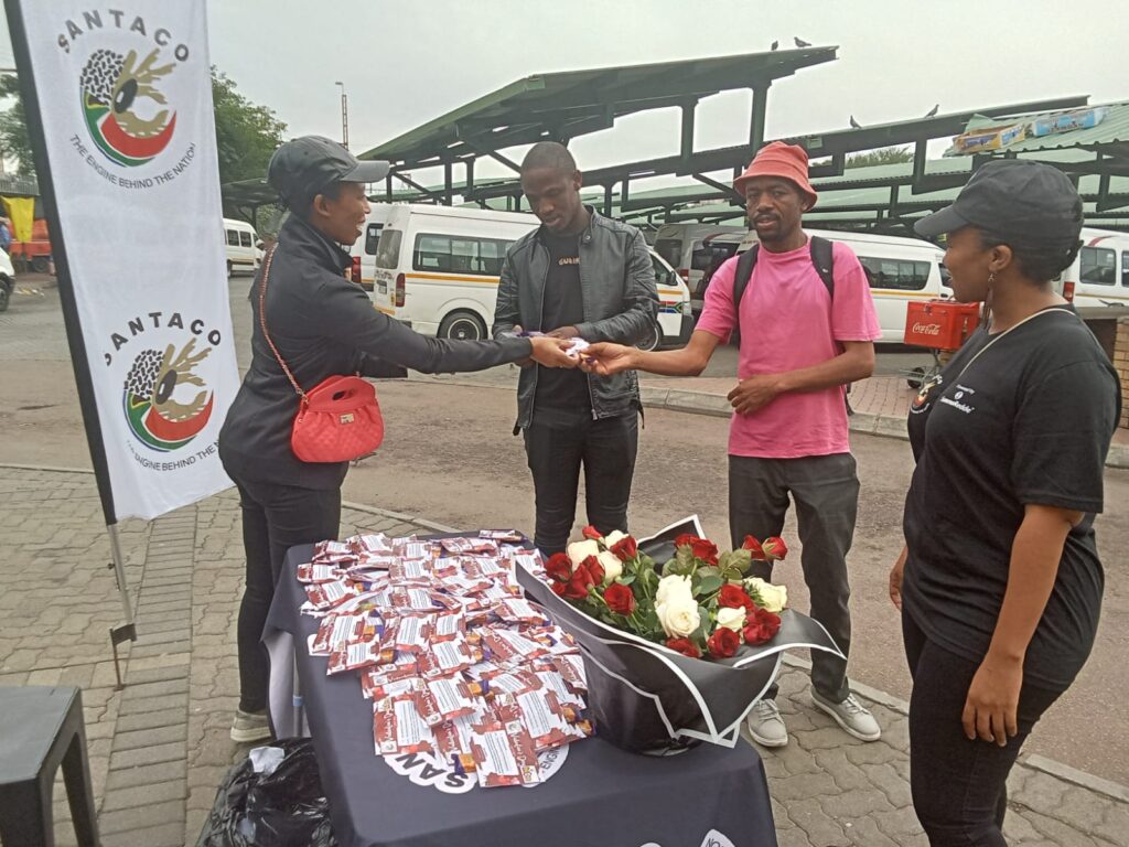 SANTACO member gives pot flower and chocolate to passengers at Bosman Taxi Rank photo by Dimakatso Modipa