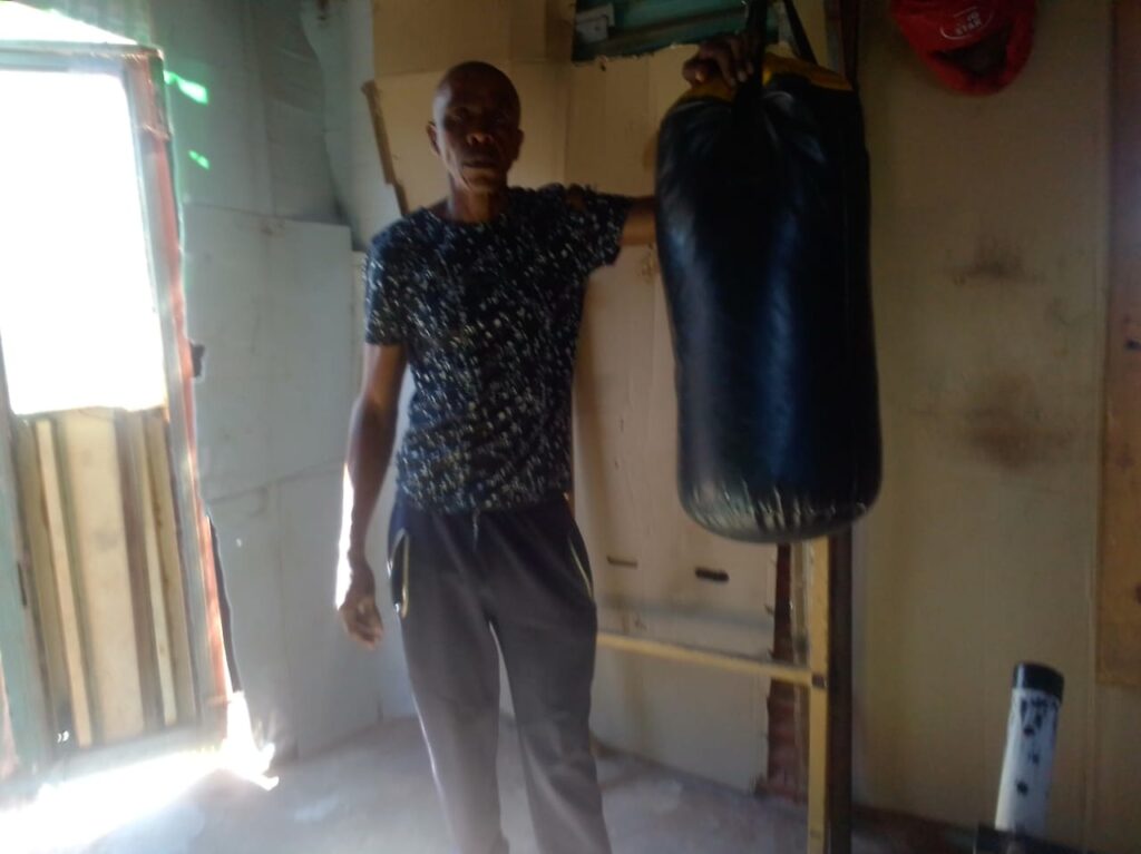 David Mogale standing next to one of his punching bags at his gym photo by Peter Mothiba